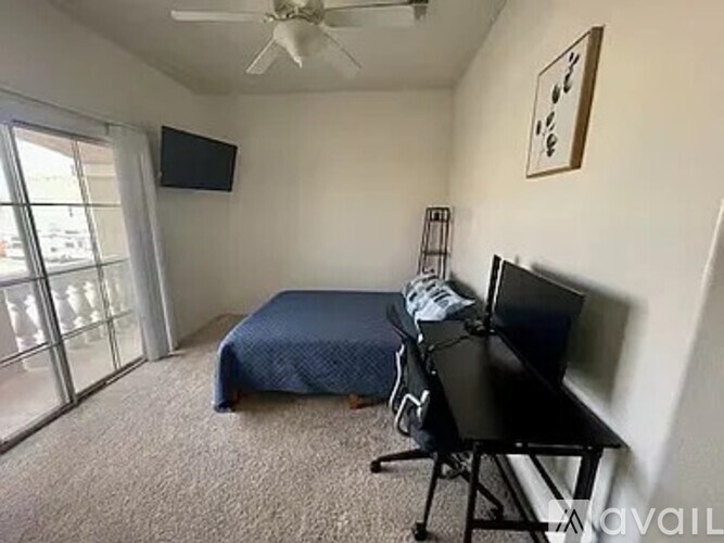 A bedroom with a bed, desk, and television.