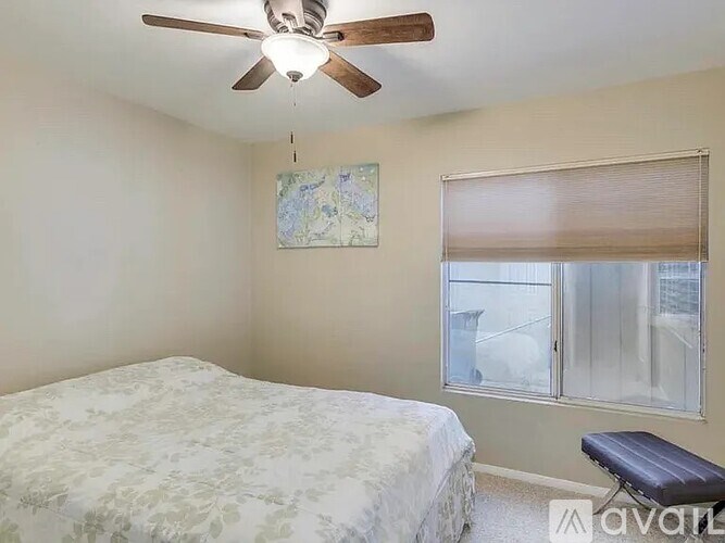 A bedroom with a bed, a ceiling fan, and a window with blinds.