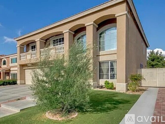 A beige house with a balcony and a tree in front.