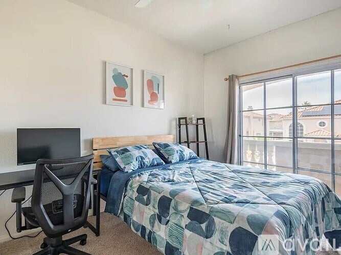 A bedroom with a bed, a desk, and a chair.