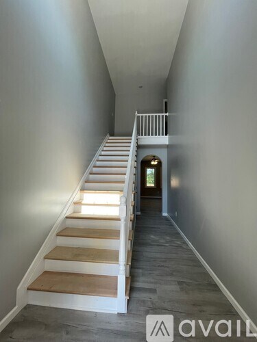 A long hallway with a staircase and a door at the end.