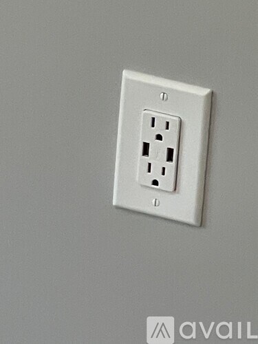 A white electrical outlet on a grey wall.