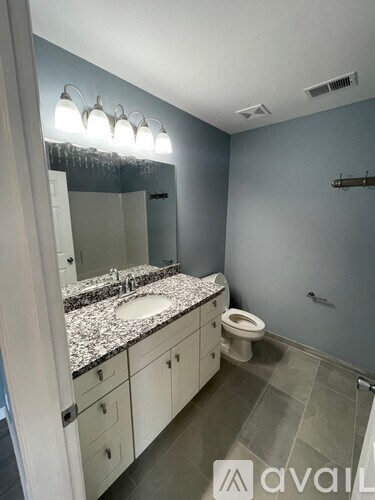 A bathroom with a sink, toilet, and a mirror.
