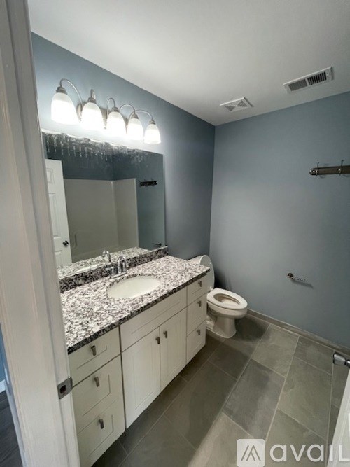 A bathroom with a sink, toilet, and mirror.