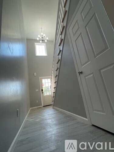 A hallway with a chandelier, a door, and a staircase.