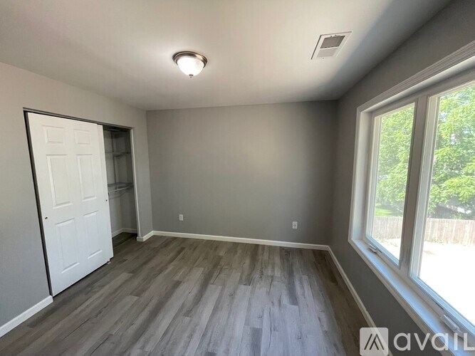 A room with a door, window, and wooden flooring.