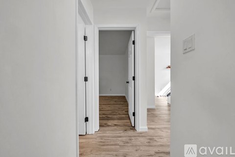 A hallway with a wooden floor and white walls.