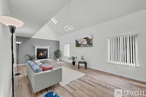 A living room with a grey couch and a fireplace.