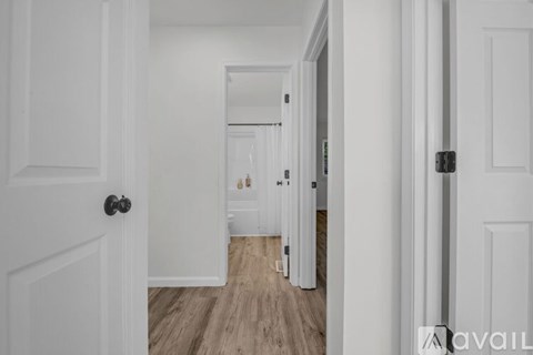 A hallway with white doors and a black handle.