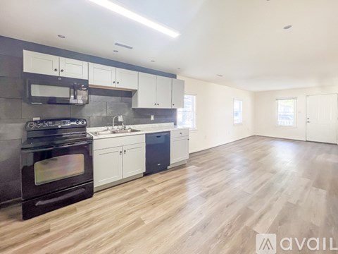 A modern kitchen with a black oven and wooden floors.