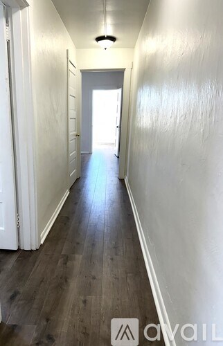 A long hallway with wood floors and white walls.