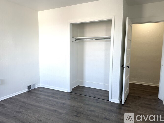 A room with a grey floor and white walls has a door open to another room.