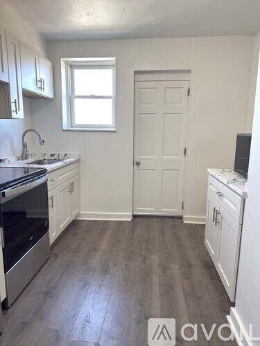 A kitchen with white cabinets and a white door.