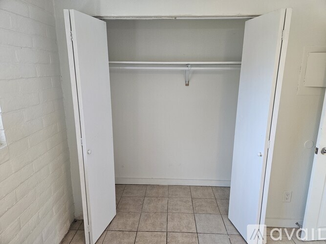 A white closet with a shelf and a door open.