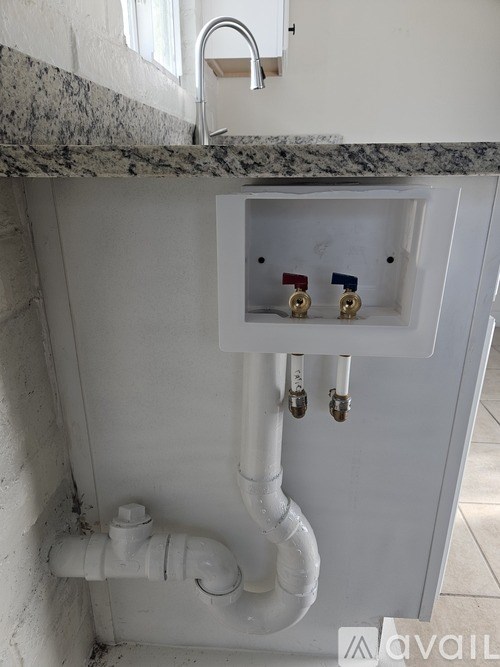 A white sink with a grey counter top and pipes.