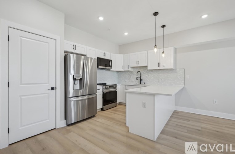 A modern kitchen with stainless steel appliances and wooden flooring.