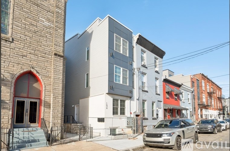 A row of modern townhouses with a car parked in front of the first one.