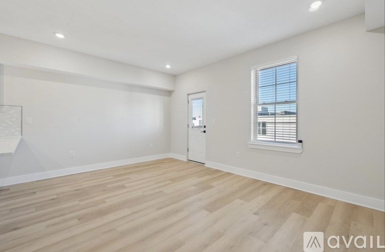 A room with wooden flooring and a window with blinds.
