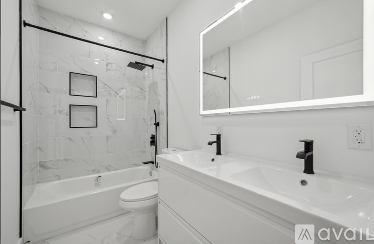 A white bathroom with a marble wall and a glass shower.