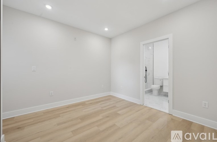 A room with wooden flooring and a white door leading to a bathroom.