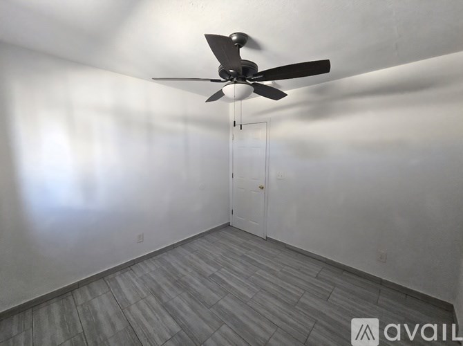 A room with a ceiling fan and a door.