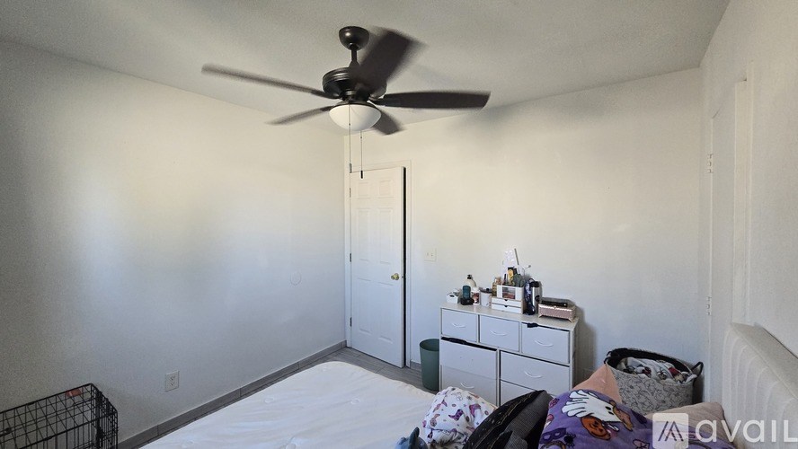 A room with a ceiling fan and a bed with a purple blanket.