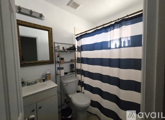 A bathroom with a toilet, sink, and striped shower curtain.