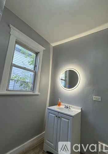 A bathroom with a round mirror and a cabinet.