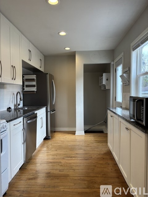 A kitchen with white cabinets and black countertops.