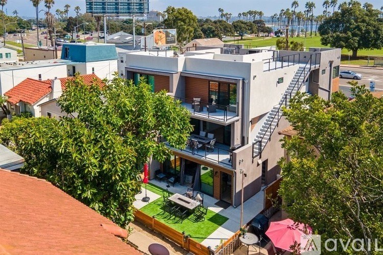 A modern house with a large patio and a red umbrella.