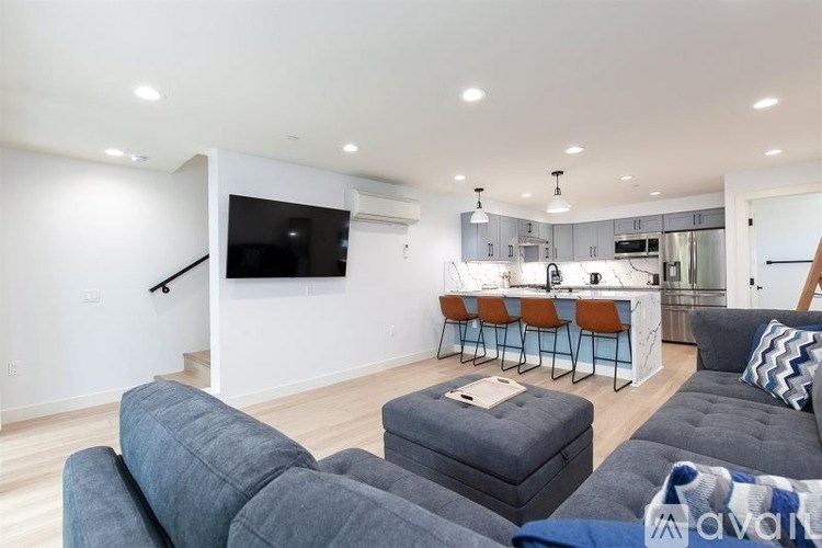 A living room with a grey couch and a television mounted on the wall.