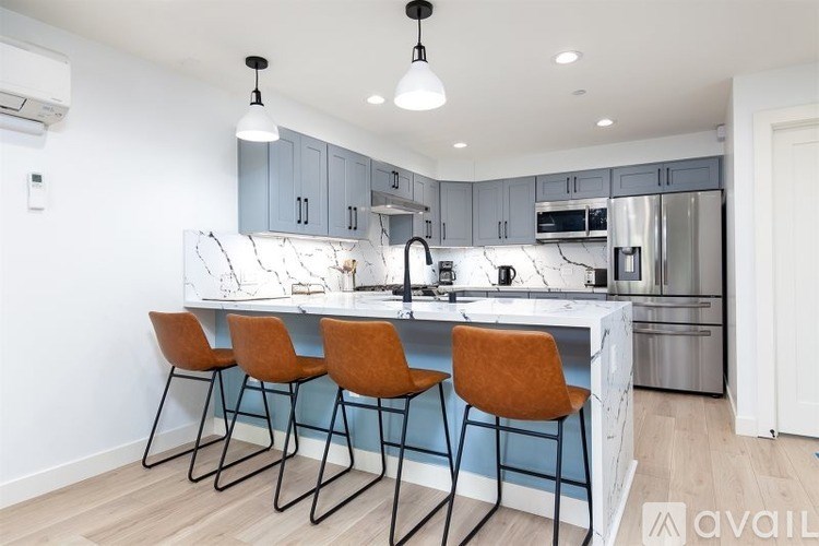 A kitchen with a white counter top and orange chairs.