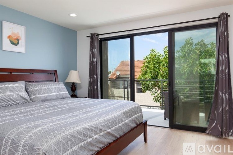 A bedroom with a large bed and a view of the backyard through the sliding glass doors.