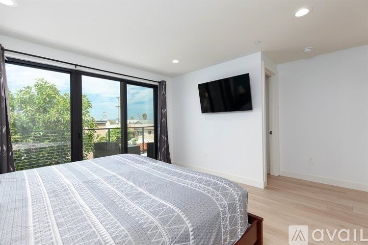 A bedroom with a large bed and a flat screen TV mounted on the wall.