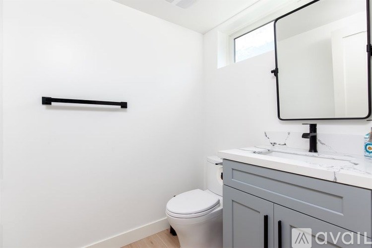 A bathroom with a toilet, sink, and mirror.