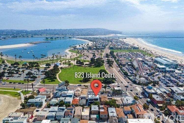 An aerial view of a beachfront area with a red marker indicating 823 Island Court.