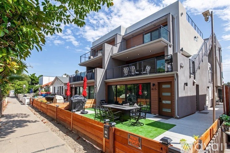 A modern two-story house with a balcony and a wooden fence.