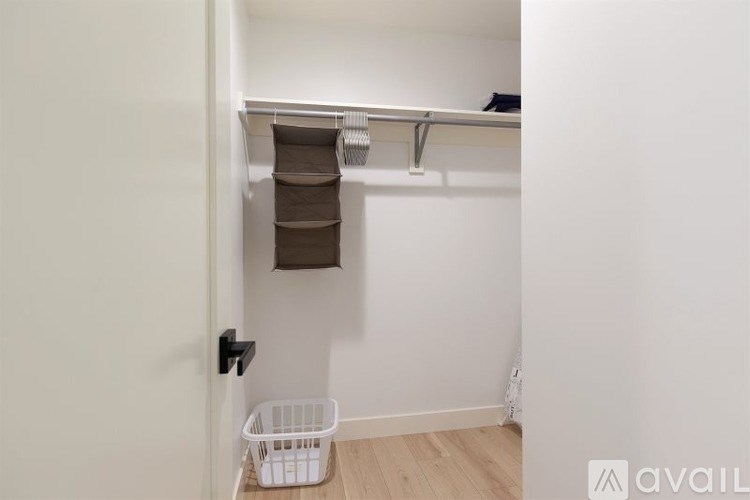 A white door with a black handle and a white basket on the floor.