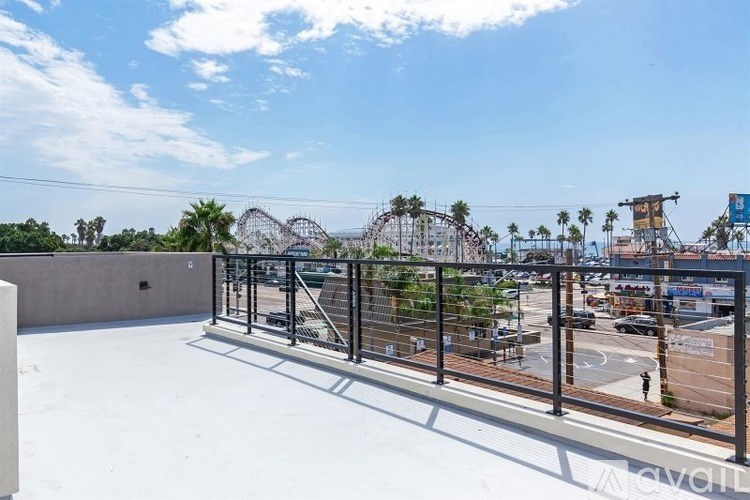 A view of a rooftop with a metal railing, a concrete wall, and a clear blue sky.