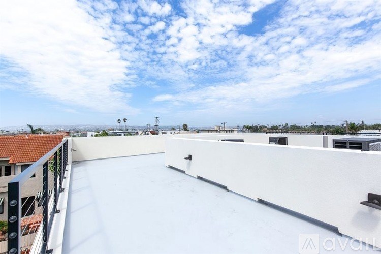 A rooftop with a white surface and a metal railing.