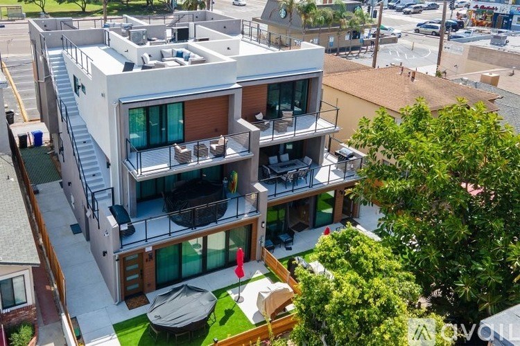 A modern multi-story house with a balcony and a patio.