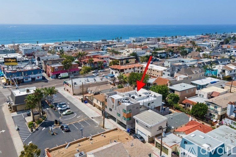 A red arrow points to a building in a city with the ocean in the background.