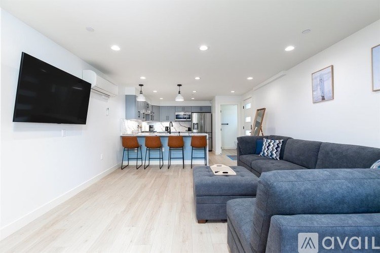A living room with a grey couch and a television on the wall.