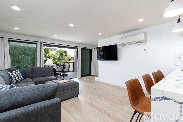 A modern living room with a grey sofa and wooden chairs.