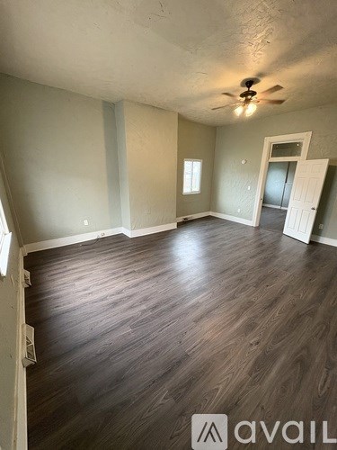 A room with wooden flooring and a ceiling fan.