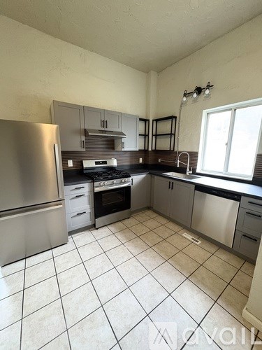 A kitchen with a stainless steel refrigerator, oven, and sink.