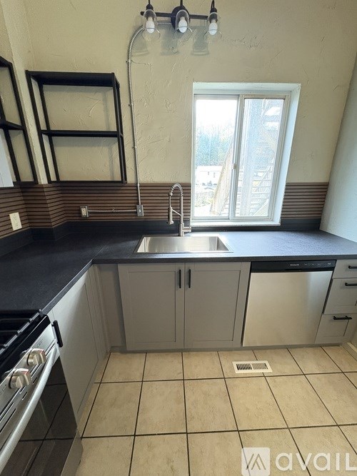 A kitchen with a sink, stove, and cabinets.