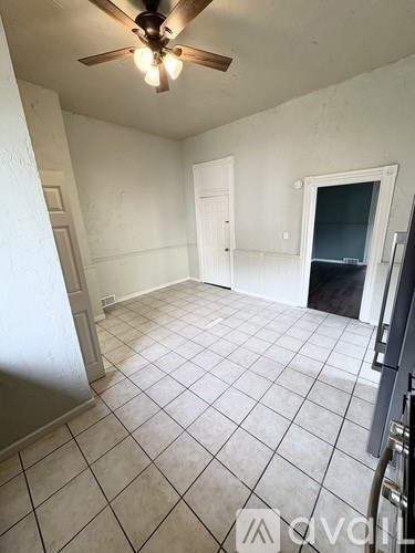 A room with a ceiling fan and tile flooring.