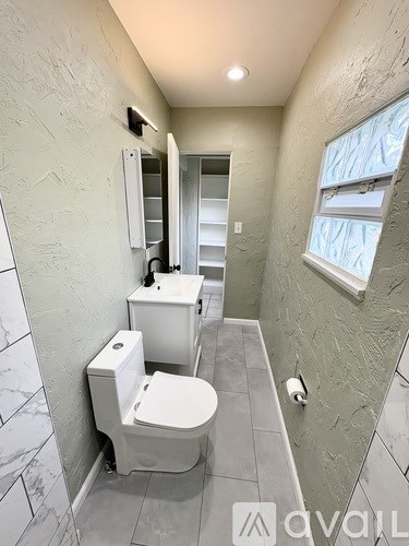 A bathroom with a toilet, sink, and mirror.