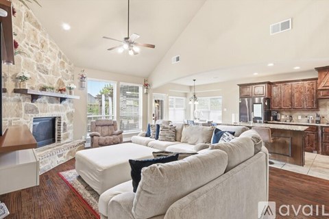 A spacious living room with a stone fireplace and a large couch.